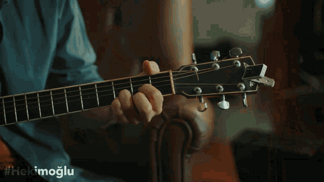 a man with a beard is playing an acoustic guitar with the hashtag #hekimoglu