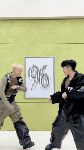 two men are dancing in front of a poster that has the number 96 on it
