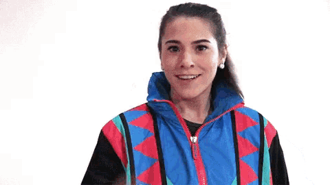 a woman wearing a colorful jacket is giving a thumbs up .