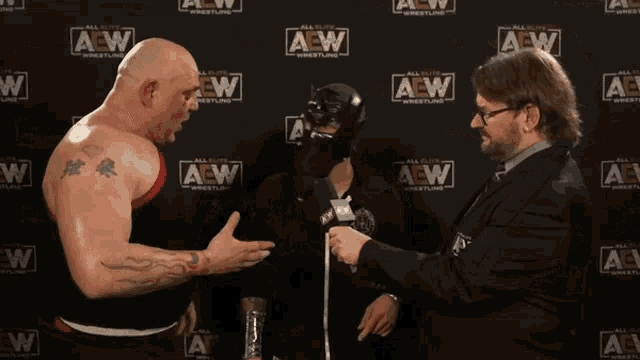 two men are standing in front of a wall that has aew written on it