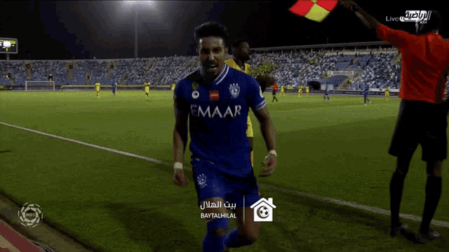 a soccer player wearing a blue emaar jersey is running on the field