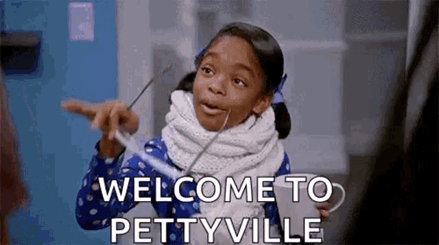 a little girl is holding a cup and pointing at the camera while saying `` welcome to pettonville '' .