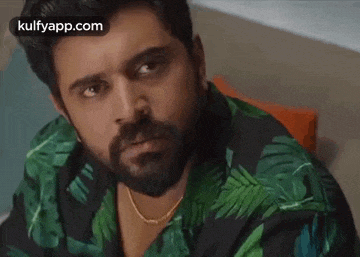 a man with a beard is wearing a green shirt with leaves on it .