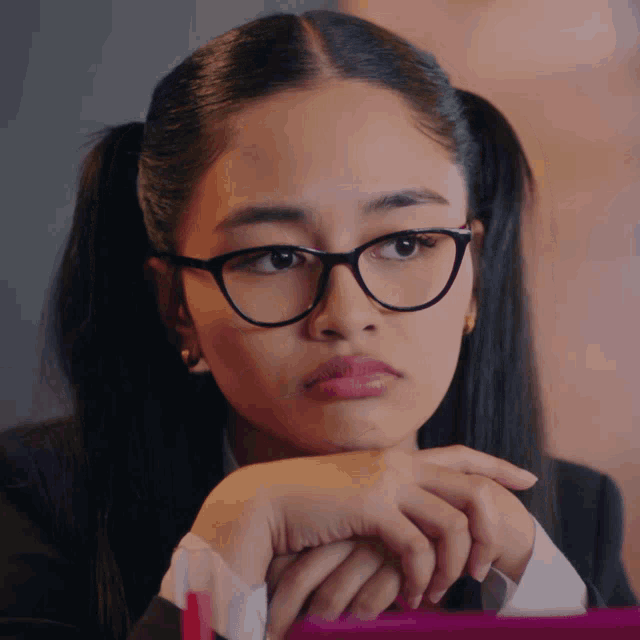 a girl wearing glasses and pigtails looks at the camera