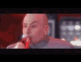 a bald man drinking a red liquid from a bottle