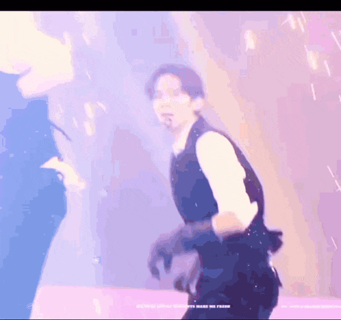 a man in a suit is dancing on a stage in front of a purple background .