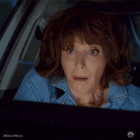 a woman is sitting in the driver 's seat of a car and making a funny face .