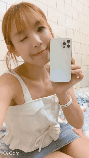 a woman is taking a picture of herself with her phone and the words o cam are on the bottom right