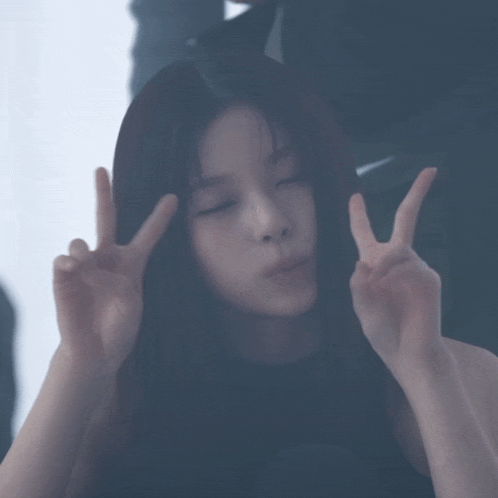 a woman with long hair is making a peace sign with her hands