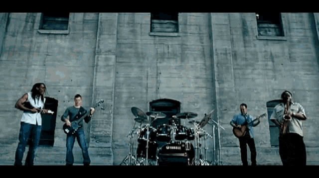 a group of men playing instruments in front of a drum set that says yamaha
