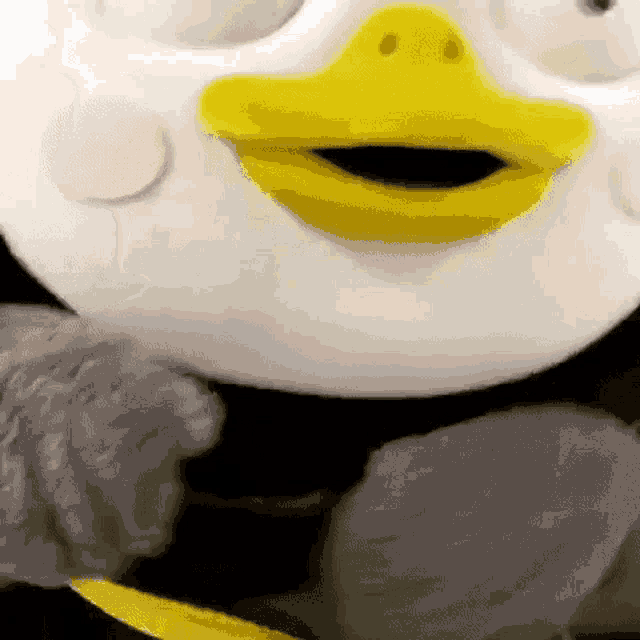 a close up of a stuffed penguin with a yellow beak and pink dots on its face .