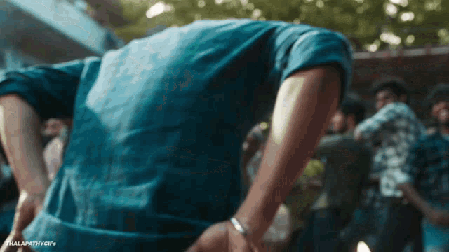 a man in a blue shirt is standing in a crowd with his hands in his pockets