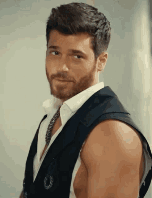 a man without a shirt is wearing a black vest