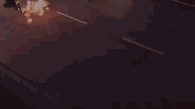 a close up of a person holding a sword in a dark room with fire coming out of it .