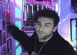 a man with a beard is standing in front of a wall with purple and blue lights on it .