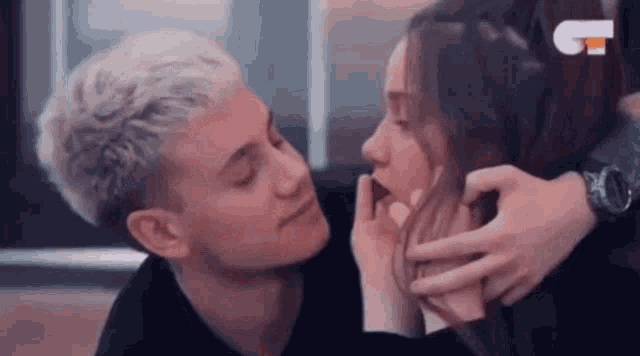 a man and a woman are kissing each other . the woman is touching the man 's face .