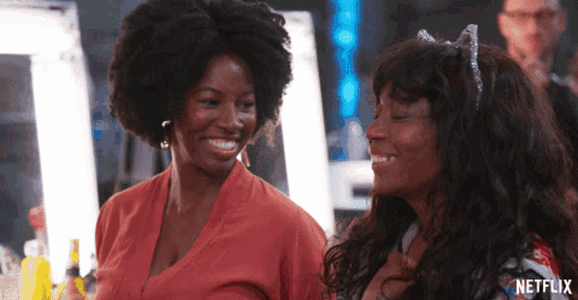 two women are smiling in front of a sign that says netflix on it