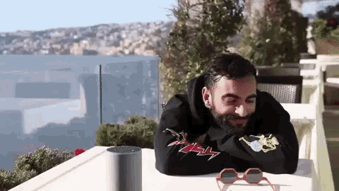 a man with a beard is sitting at a table with his head resting on his arm