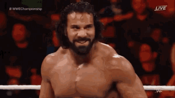 a shirtless wrestler with a beard is standing in a wrestling ring .