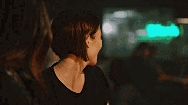 a woman 's back is shown in a dark room with a green light behind her