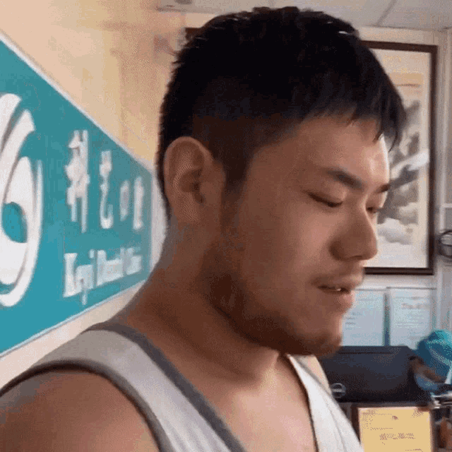 a man in a tank top stands in front of a sign that says ' keji dental ' on it