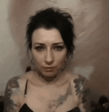 a woman with a lot of tattoos on her arms is making a face .