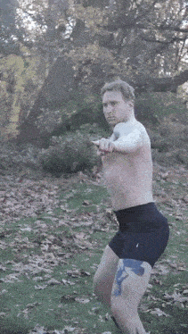 a shirtless man with a tattoo on his leg is running in a field
