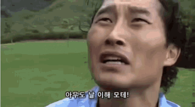 a man in a blue shirt is making a funny face with korean writing on his face