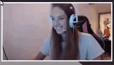 a woman wearing headphones and a microphone is smiling while sitting in front of a computer screen .