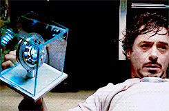 a man with a beard is holding a glass cube with a light inside of it