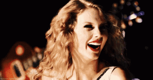 taylor swift is laughing with her mouth open and red lipstick on her lips .