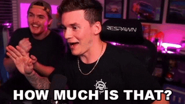 a man in a black shirt is sitting in a gaming chair while another man applauds behind him .