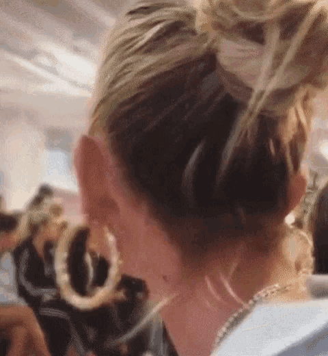 a close up of a woman 's ear with hoop earrings and a bun in her hair .