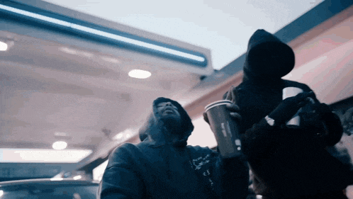 a man in a hoodie is holding a cup that says mcdonald 's