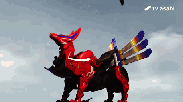 a red robot with a blue tail and a tv asahi logo in the background