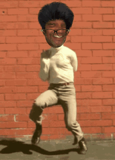 a man wearing glasses and a turtleneck is dancing in front of a red brick wall