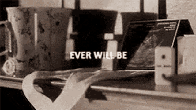 a black and white photo of a shelf with a heart and the words `` ever will be '' .