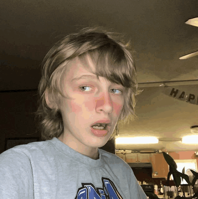 a young boy with red cheeks and a gray shirt that says ' nc ' on it