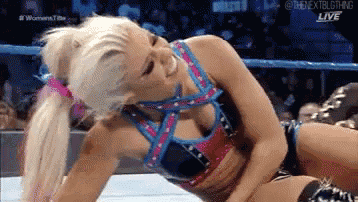 a woman is laying on the ground in a wrestling ring while smiling .