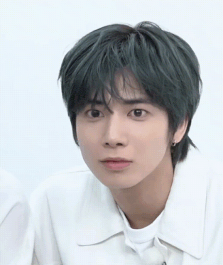 a close up of a person 's face with green hair and a white shirt