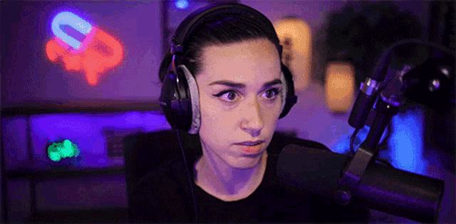 a woman wearing headphones is sitting in front of a microphone and making a face .