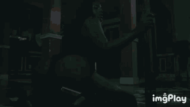 a woman in a black bodysuit is sitting on the floor in the dark .