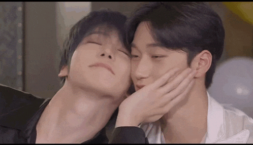 a couple of young men are kissing each other on the cheek .