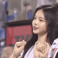 a close up of a girl making a heart shape with her fingers .