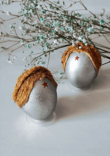two silver balls with brown hair and a red star on the top