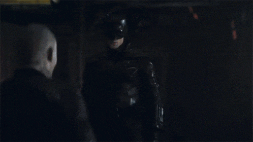 a man is standing next to another man in a dark room .