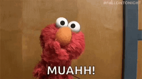 elmo from sesame street is making a funny face and saying muahh !