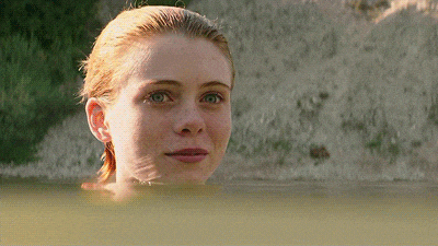 a woman is swimming in a body of water looking at the camera