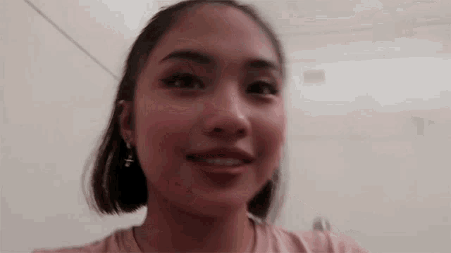 a close up of a woman 's face with short hair and earrings smiling .