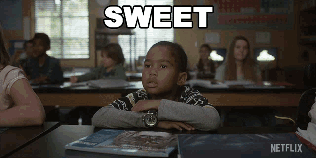 a boy sits at a desk in a classroom with the word sweet written above him